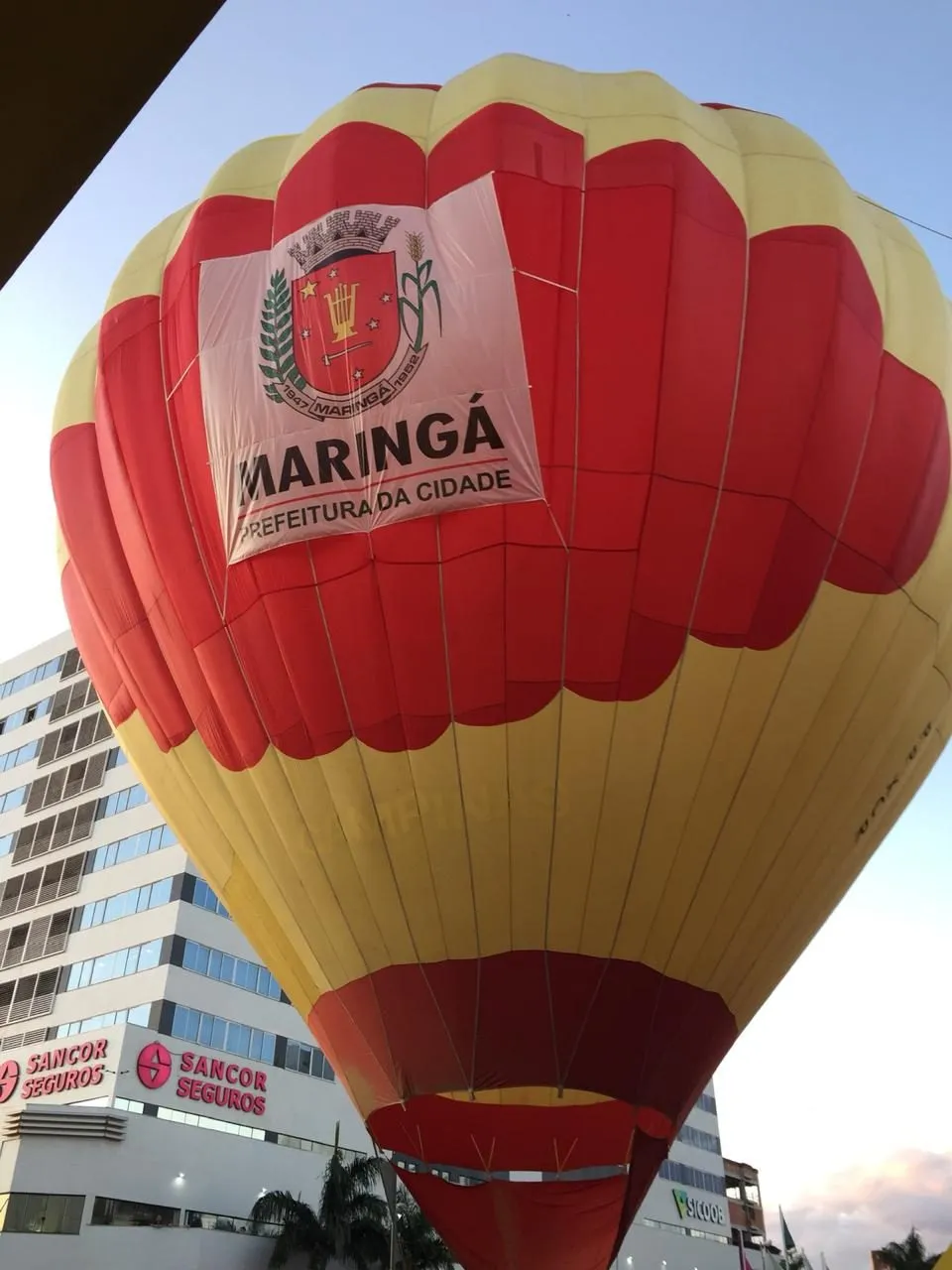Balão vermelho e amarelo com marca em voo sobre a cidade