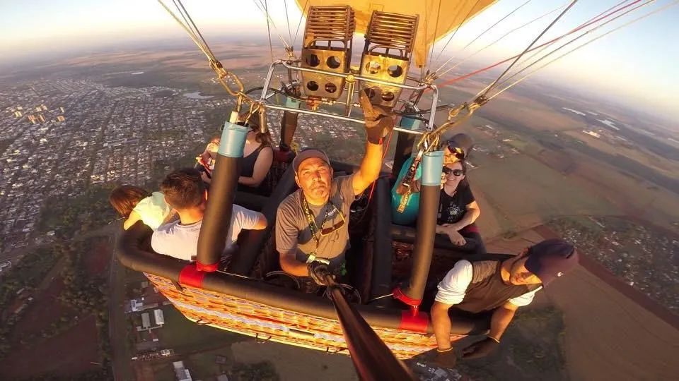 Passageiros no cesto do balão vistos de cima, com a cidade lá embaixo